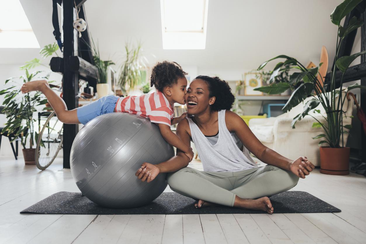 Mother And Daughter laughing while doing yoga on a mat and exercise ball