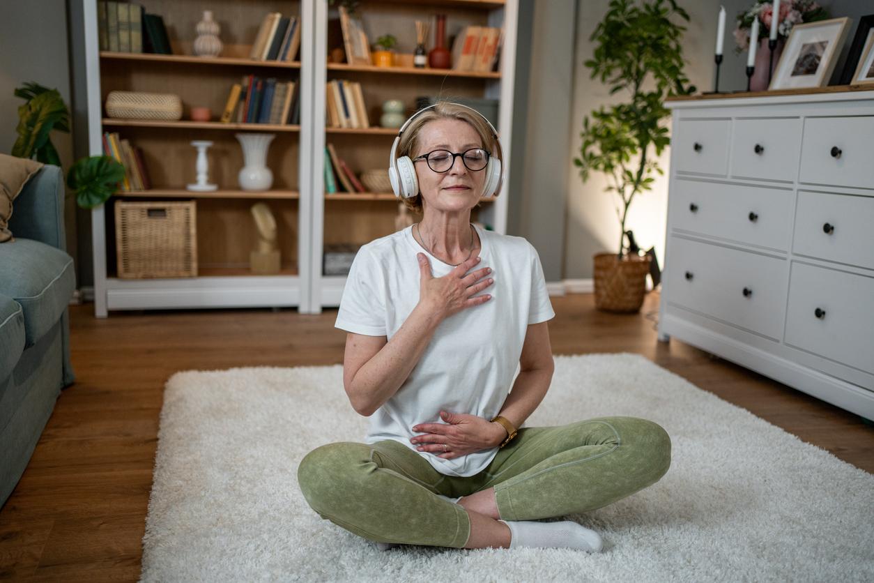 Middle-aged woman listening to a guided yoga meditation in her living room