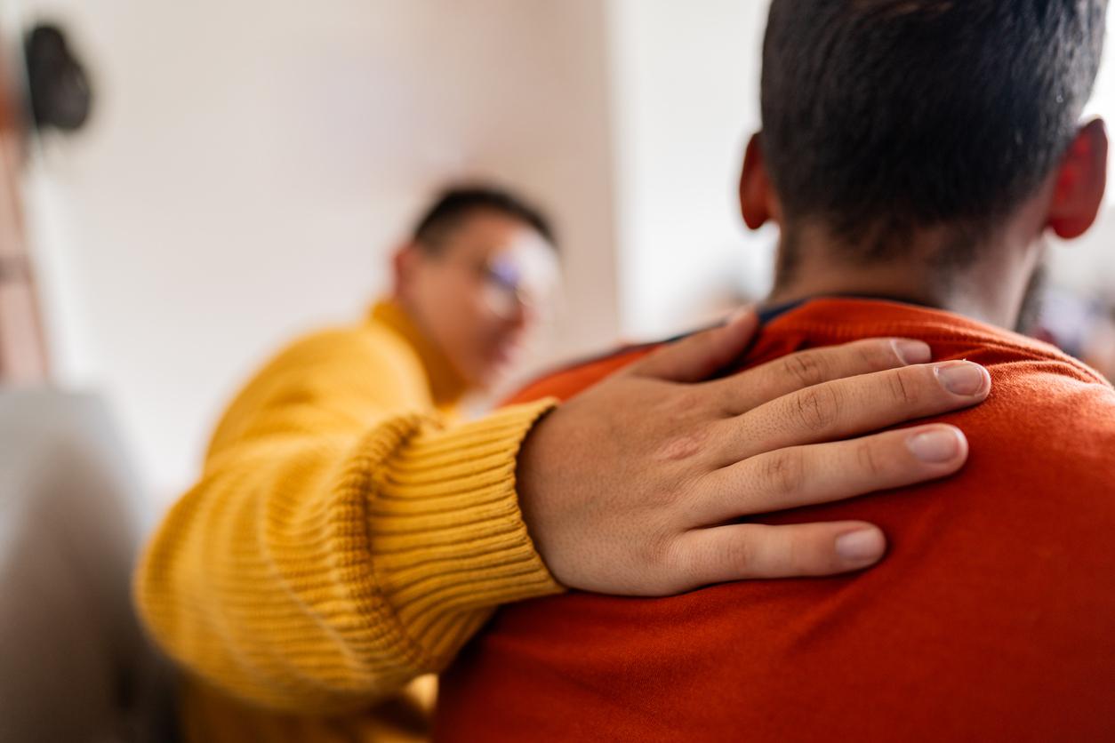 Therapist hand on shoulder, speaking with a patient.