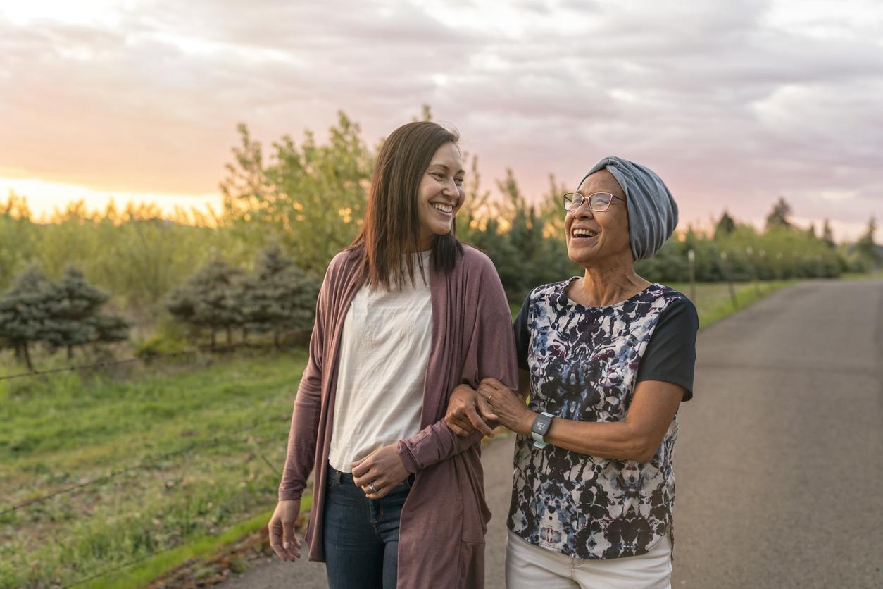 Mother and daughter walk arm in arm together during sunset